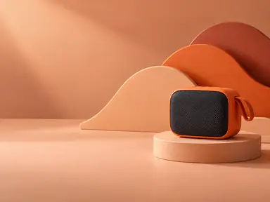 An orange portable speaker in front of matte peach and terracotta sculptural waves.