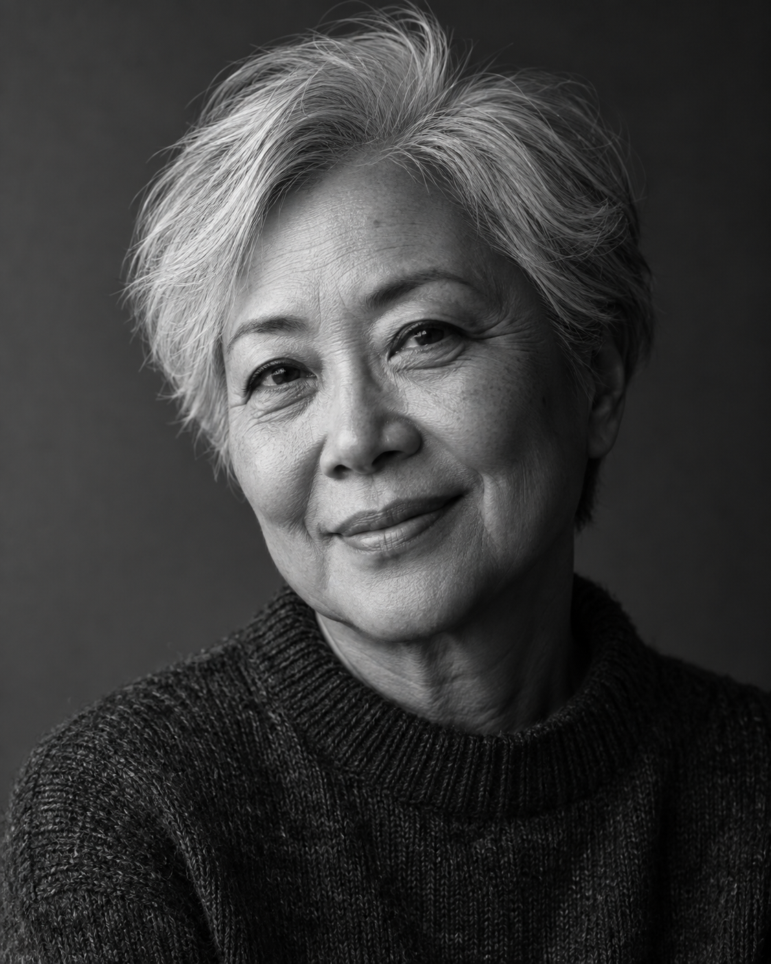 Black-and-white portrait of an older woman with silver hair, softly lit from the side.